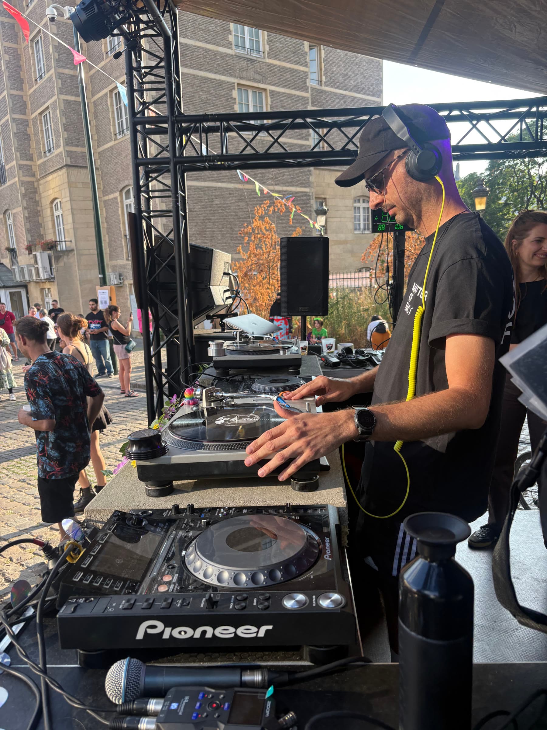 A DJ in a cap working the CDJs under the rig.