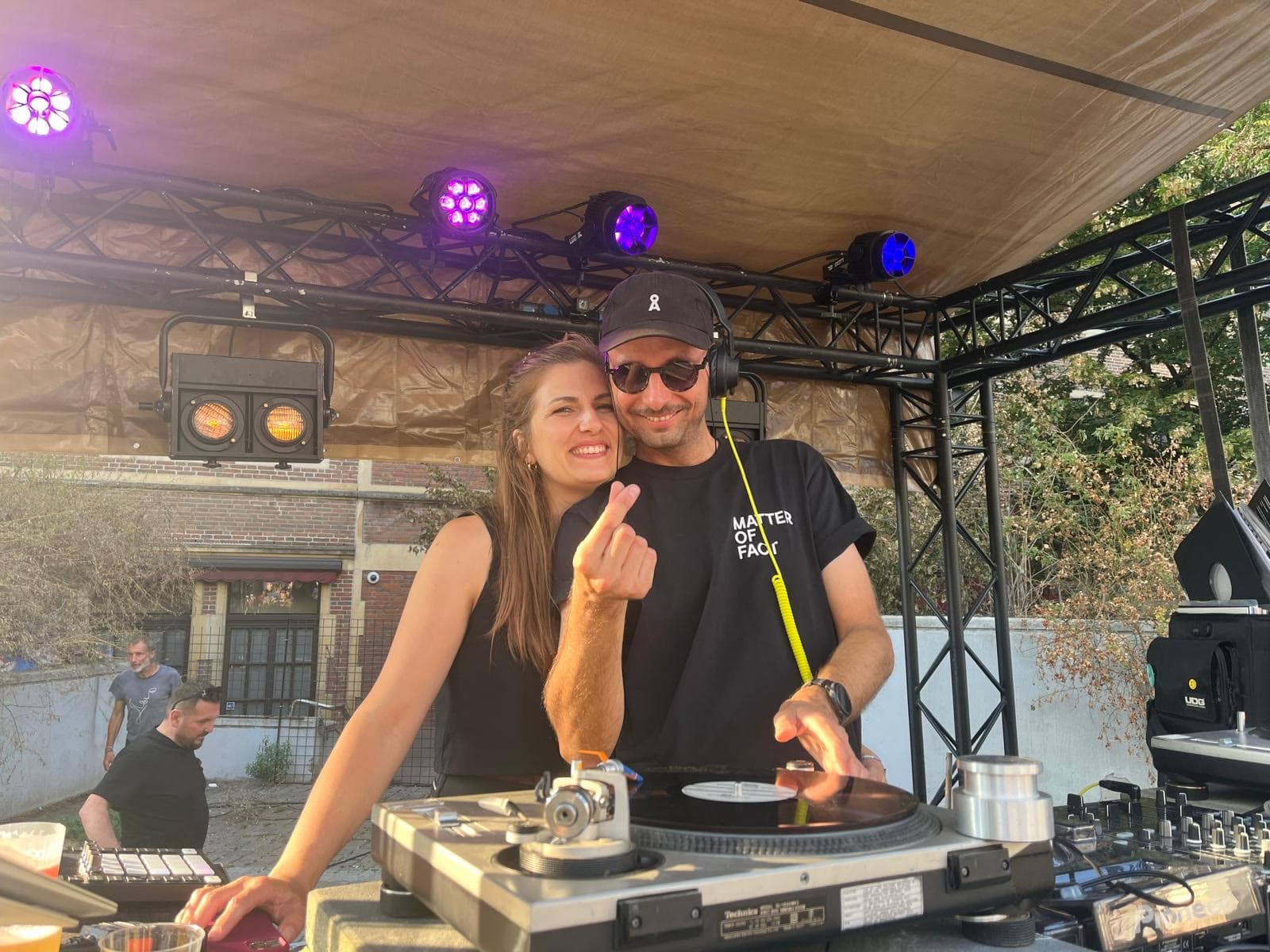Two of the crew side by side behind the decks, mid-laugh.
