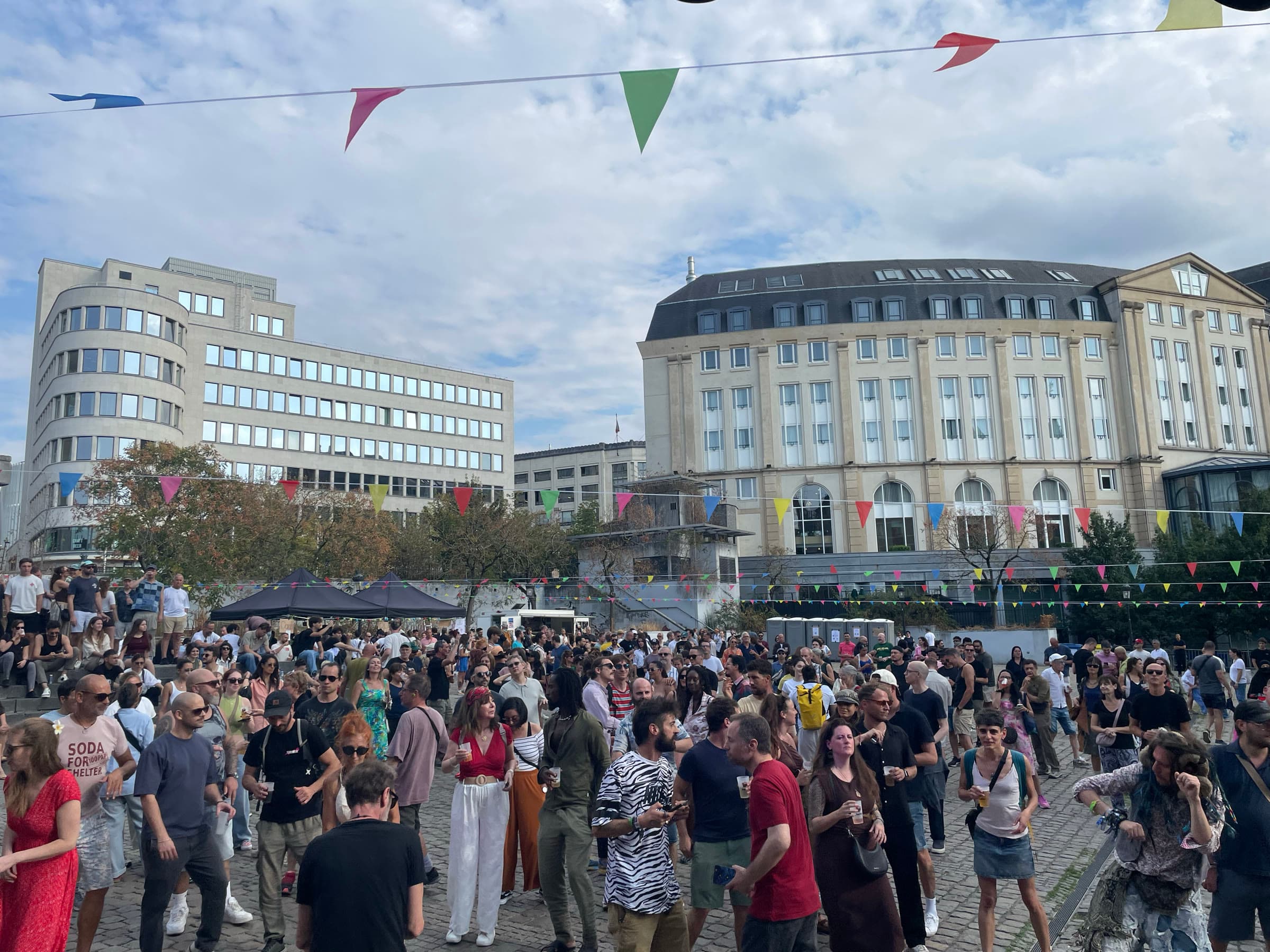 A wide view of the full crowd across the square under strings of bunting.