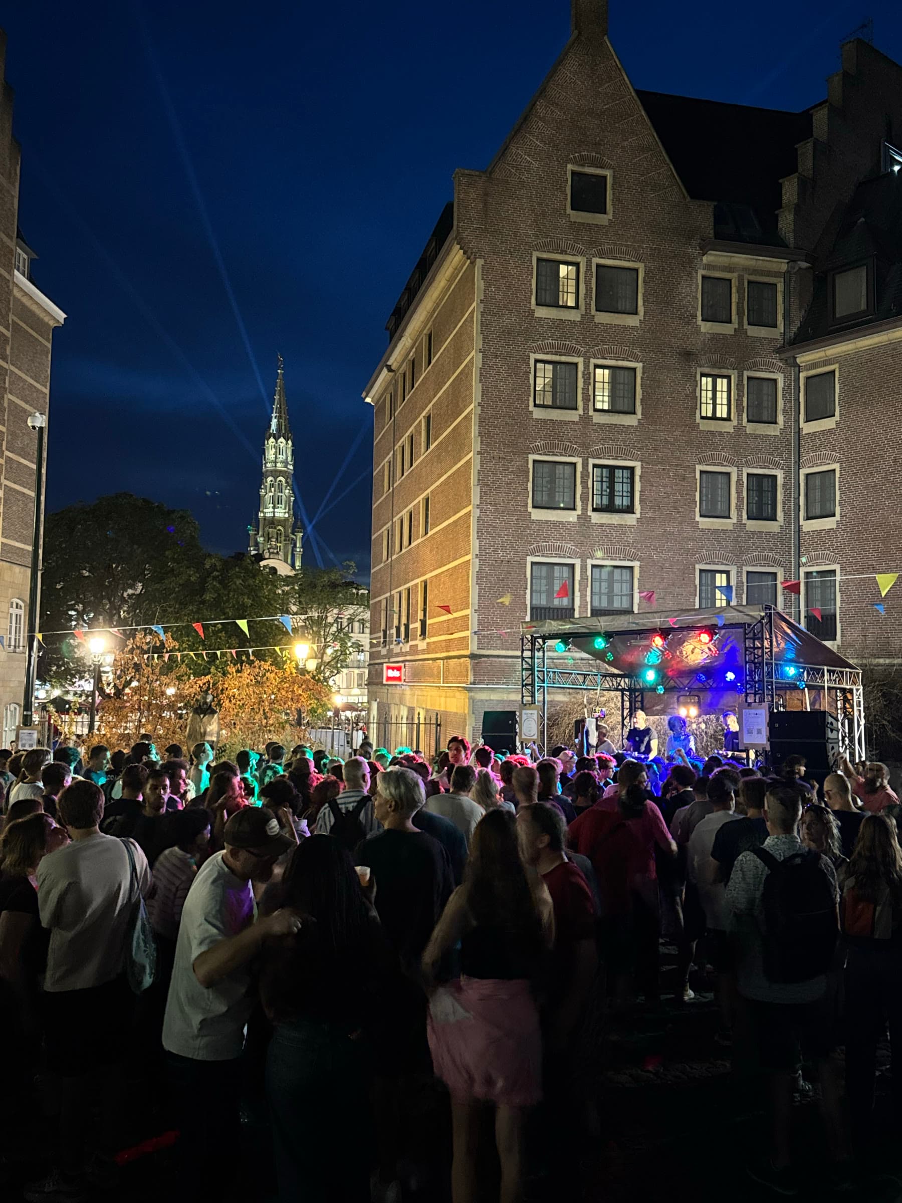 The square at night, the church tower lit above the crowd.